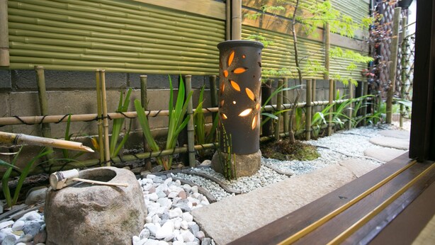 Un jardin japonais traditionnel agrémenté d’une lanterne en pierre, d’une clôture en bambou et d’un sentier.