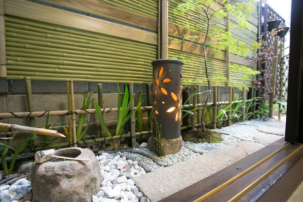 Experience serenity in this tranquil outdoor space, featuring a traditional Japanese stone lantern, bamboo fence, and lush greenery.