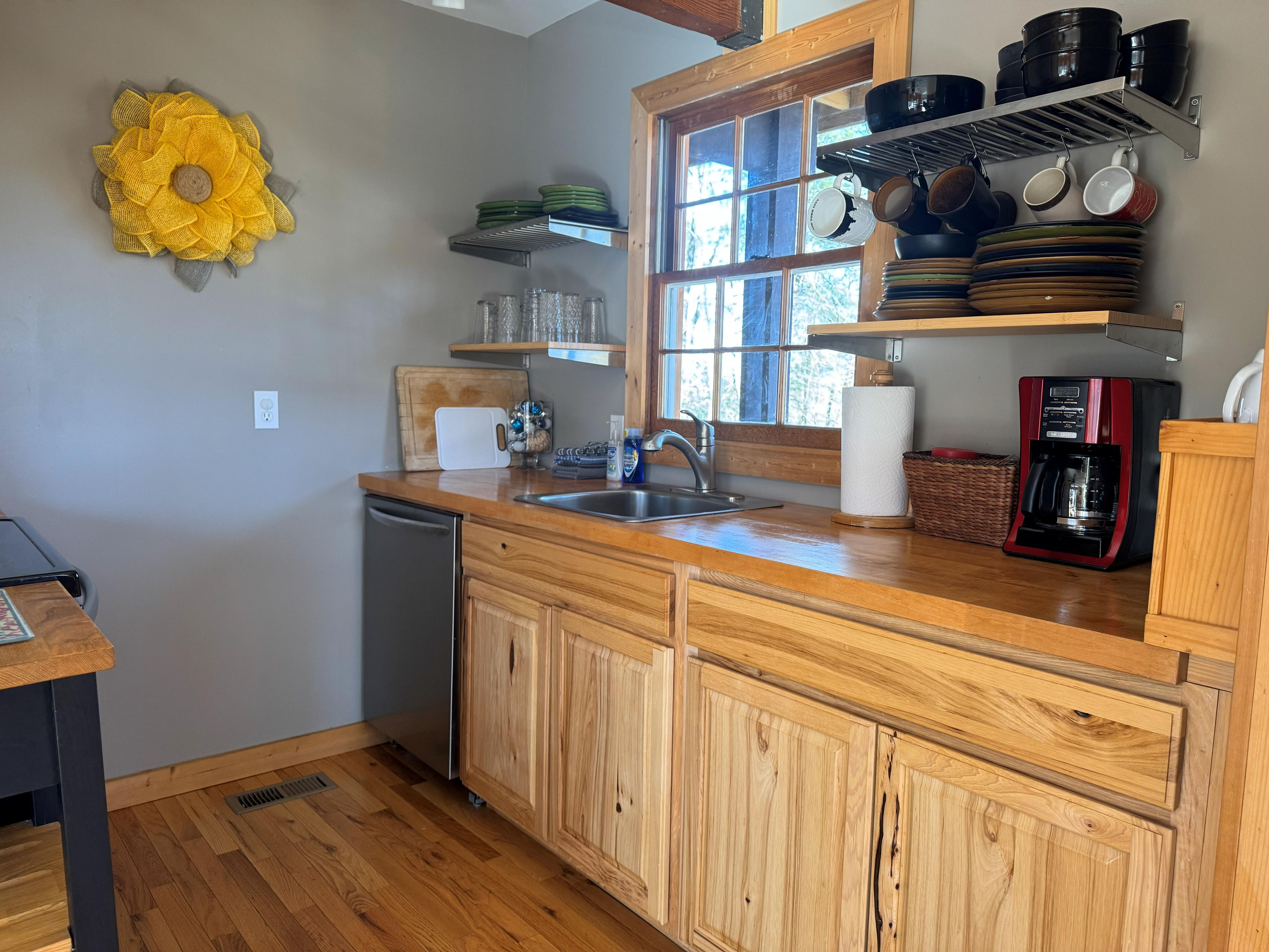 Una cocina con armarios de madera, un fregadero, una cafetera y una ventana con vistas.