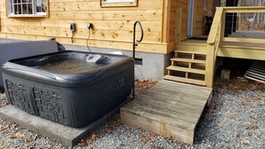 Eine Holzhütte mit Whirlpool, einer Holzterrasse und einer Treppe, die zu einer Tür führt.