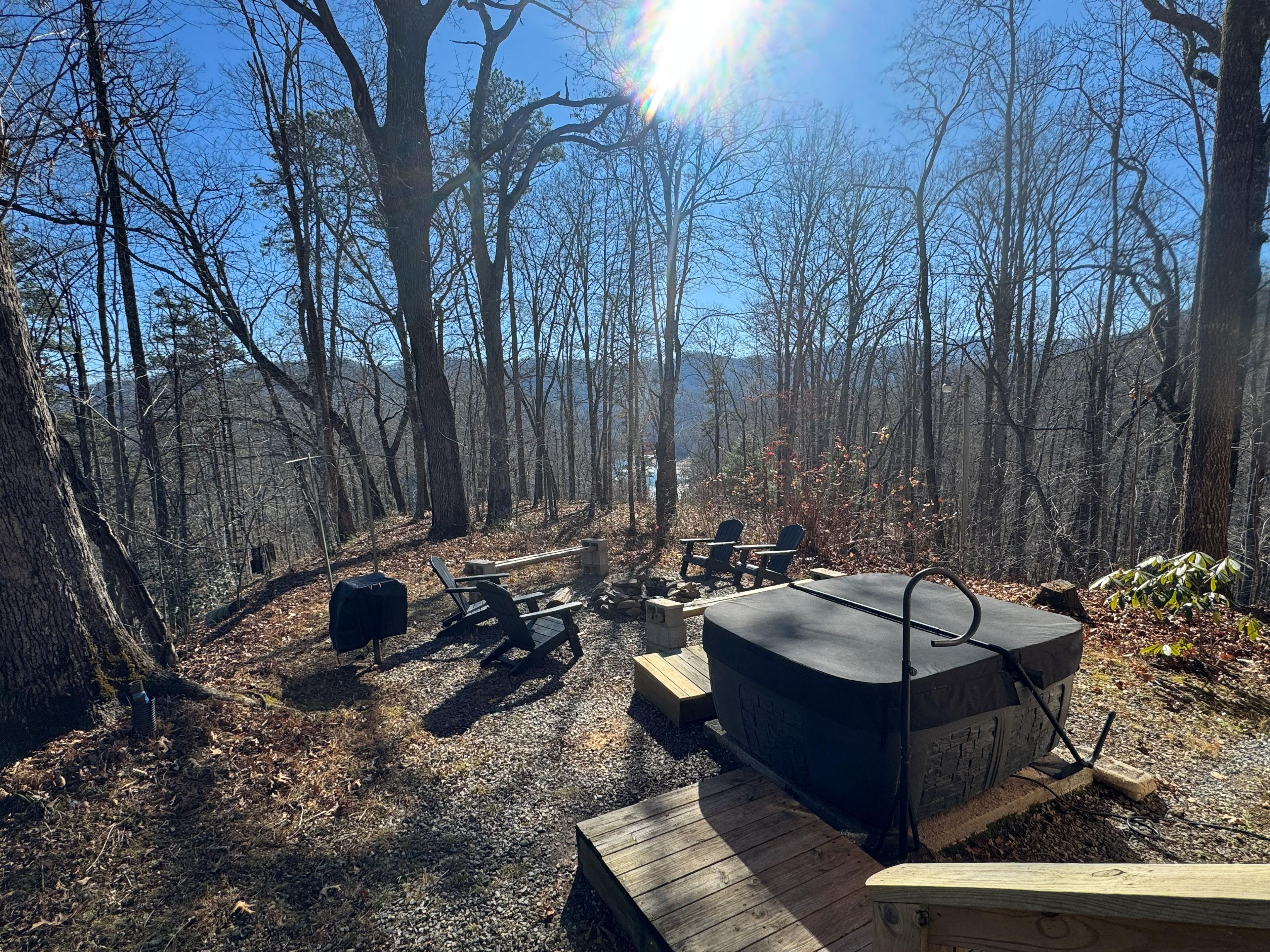 Un terrain de camping équipé d’un barbecue, de sièges et offrant une vue sur la forêt.