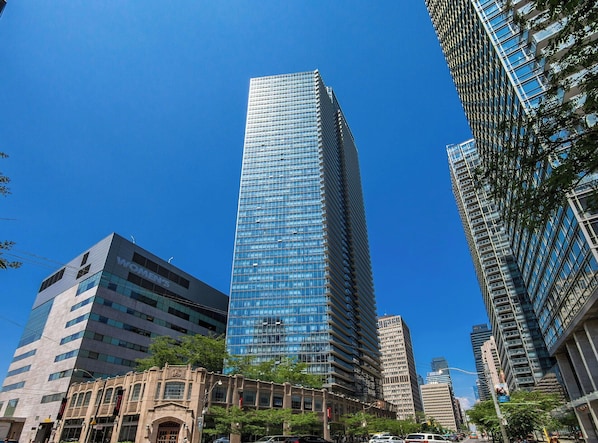 A tall, modern skyscraper with a glass facade, surrounded by other buildings.