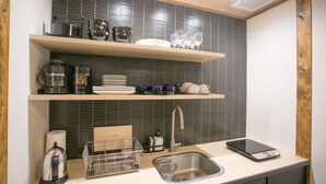 A modern kitchen with black tiled backsplash, wooden shelves, and stainless steel appliances. - Shichihonmatsu Machiya ICHI (Kyoto)