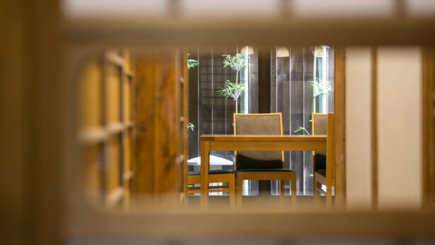 A traditional Japanese room with tatami flooring, a low wooden table, and a chair. - Shichihonmatsu Machiya ICHI (Kyoto)