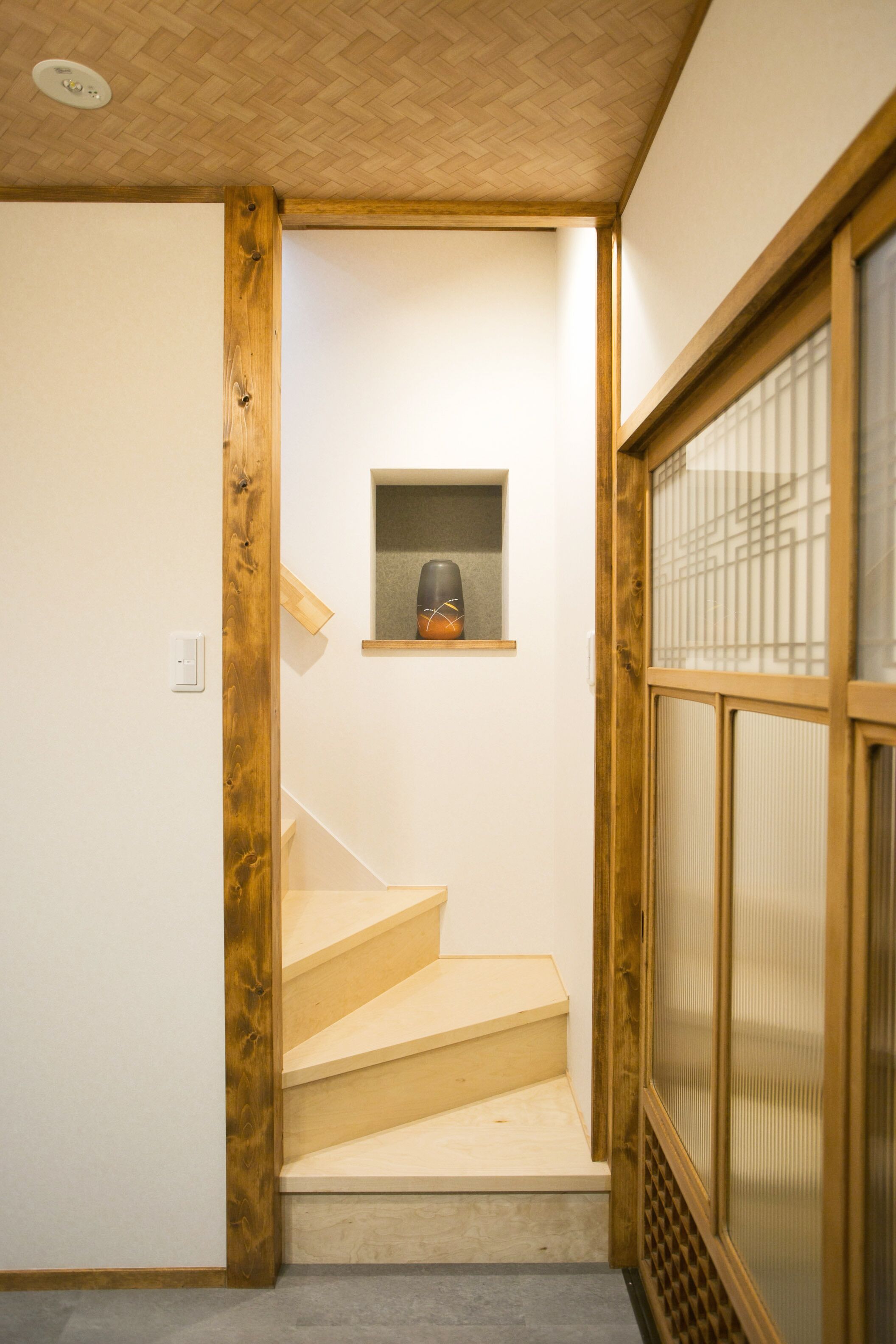 A staircase with wooden steps leading to a small shelf with a kettle.
