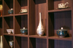 A wooden shelf with various ceramic items including a vase, bowls, and a teapot.