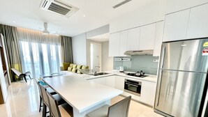 Cozinha moderna com ilha central, eletrodomésticos de aço inoxidável e área de refeições com cadeiras.