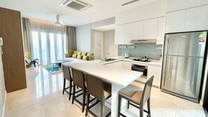 Cozinha moderna com ilha central, eletrodomésticos de aço inoxidável e área de refeições com banquetas de bar.