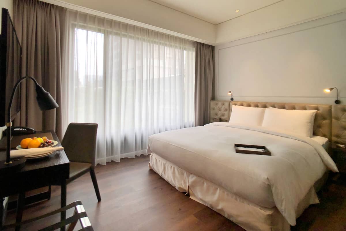 Una habitación de hotel con una cama grande, un escritorio con lámpara y una silla.