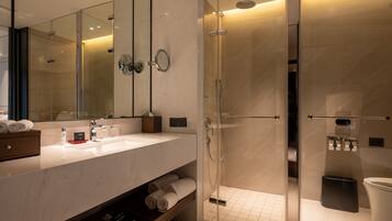 A modern bathroom with a glass-enclosed shower, a large mirror, and a marble countertop.