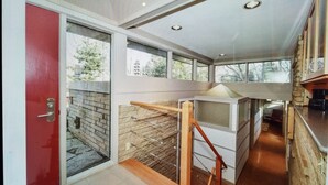 Ein modernes Interieur mit einer roten Tür, großen Fenstern und einer Küchenzeile mit Steinwand und Holzausleger.