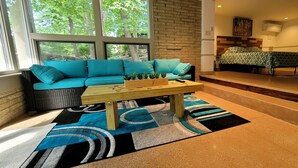 Ein gemütliches Zimmer mit einem türkisblauen Sofa, einem Holztisch und einem Bett mit einem gemusterten Bettbezug.