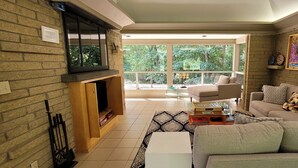 Ein Wohnzimmer mit Kamin, einer Couch, einem Couchtisch und einem großen Fenster mit Blick auf Grünflächen.