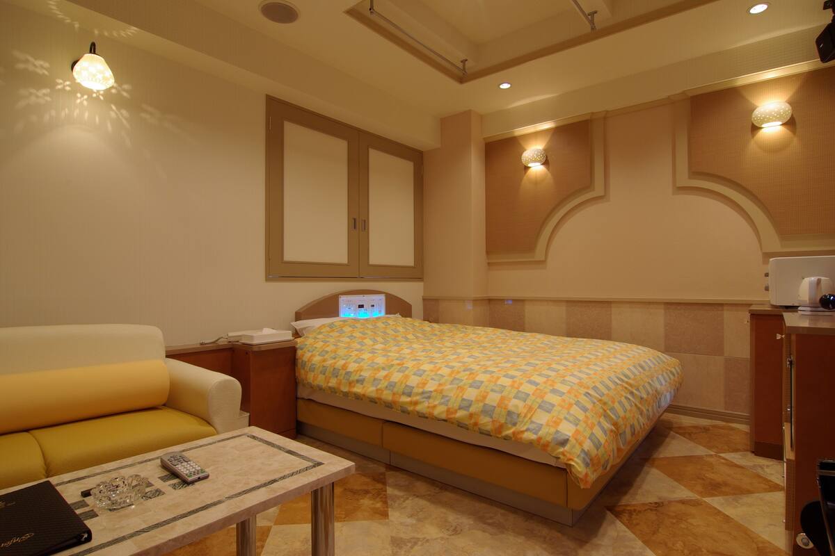 Una habitación de hotel con una cama, un sofá, una mesita y una mesita de noche.
