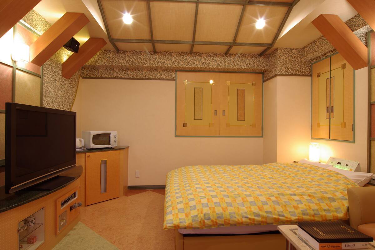 Un dormitorio con cama, televisión, microondas y escritorio con computadora.