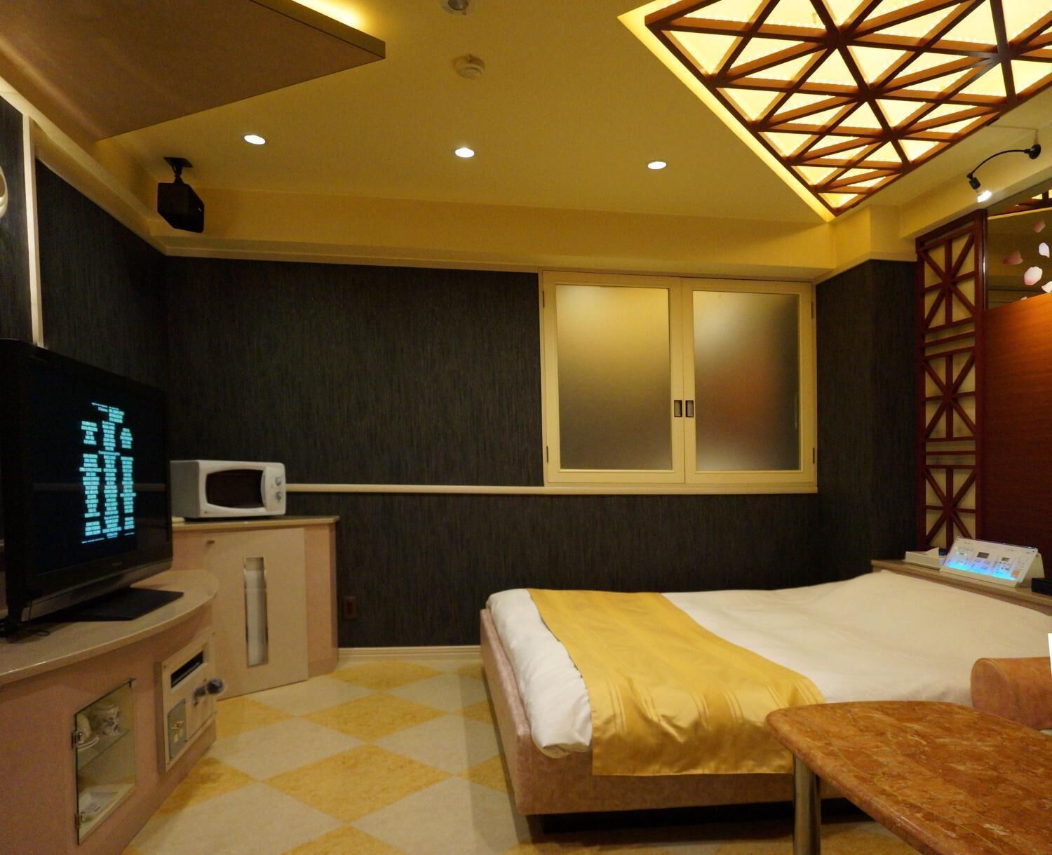 Habitació d'hotel amb un llit, televisió, microones i escriptori.
