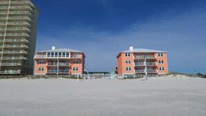 Een hotel aan het strand met meerdere verdiepingen, balkons en een zandstrand.