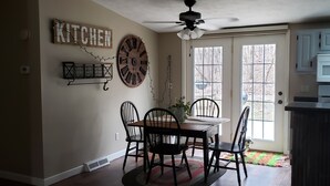 A dining area with a wooden table and chairs, a ceiling fan, and a kitchen sign on the wall. - Secluded Rustic Cabin (Cashton)