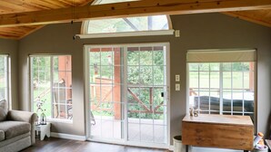 A spacious room with a high ceiling, large windows, and a wooden ceiling fan. - Secluded Rustic Cabin (Cashton)