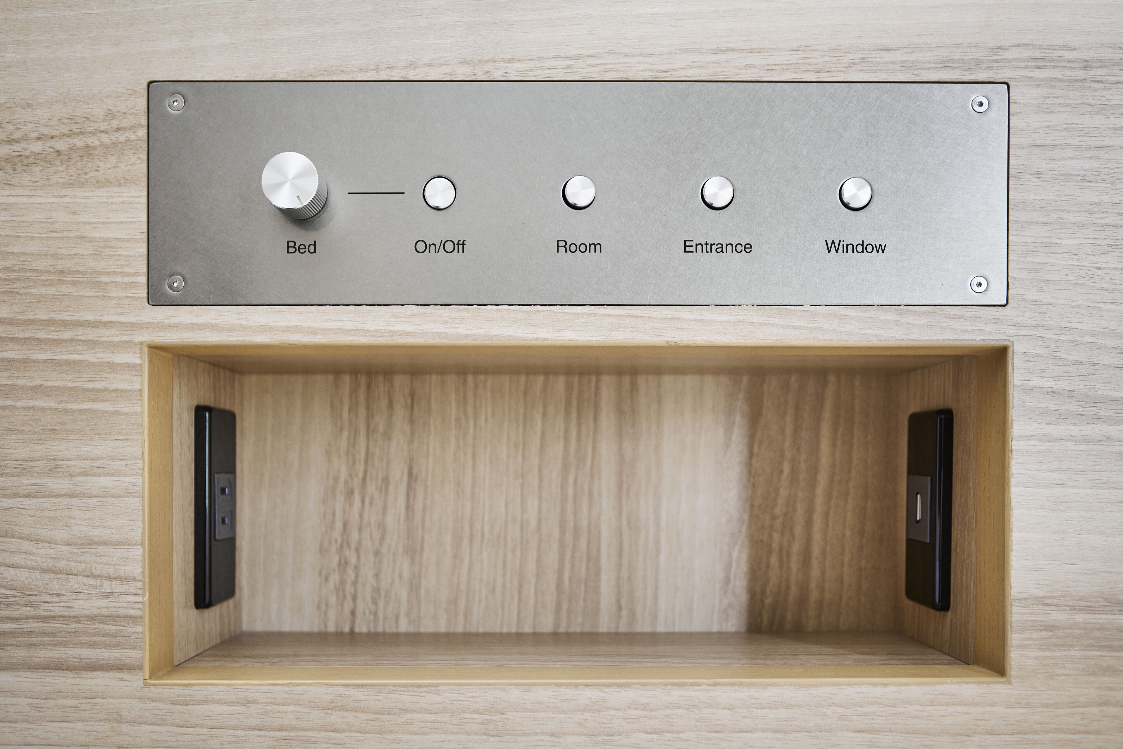 Un panel de control con cinco botones etiquetados como Cama, Encendido/Apagado, Habitación, Entrada y Ventana.