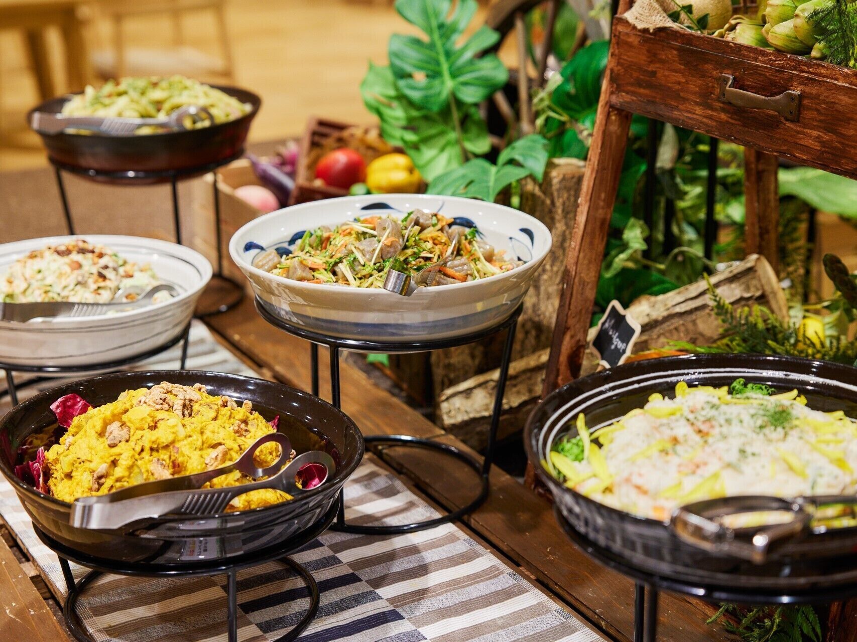 A buffet table with various dishes, including salads, rice, and a dish with nuts.