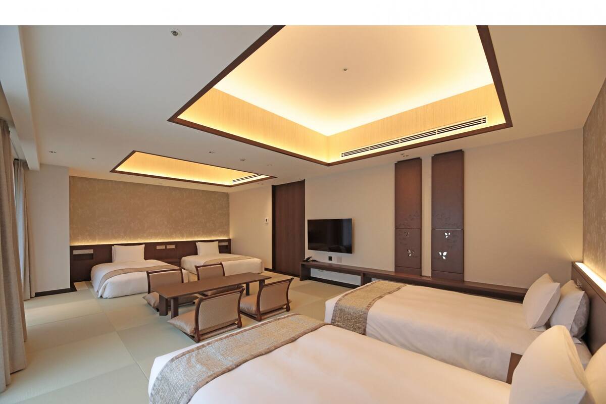 A modern hotel room with a large bed, a desk, and a TV.