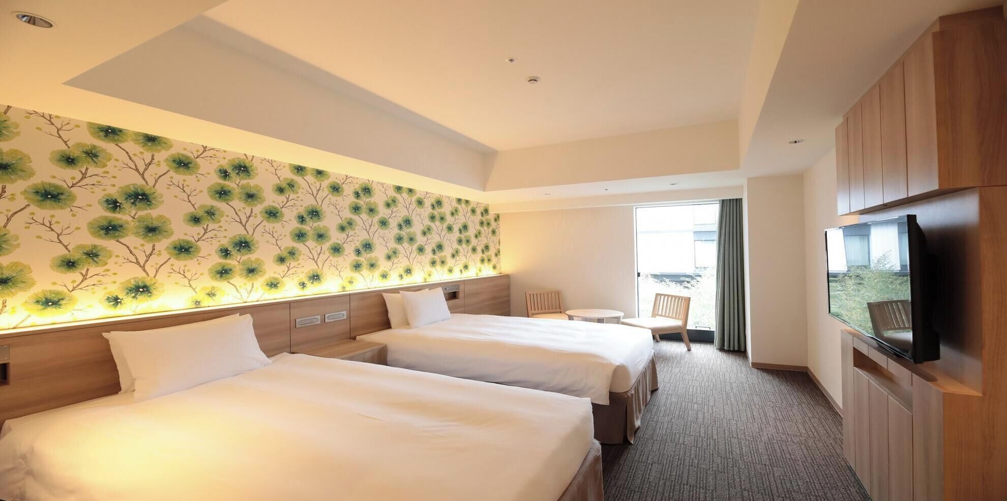 Ett hotellrum med två sängar, en TV, ett litet bord och utsikt över omgivningarna.