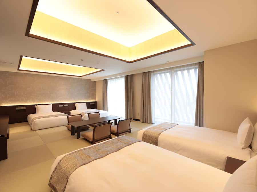 A hotel room with two beds, a desk, and a television.