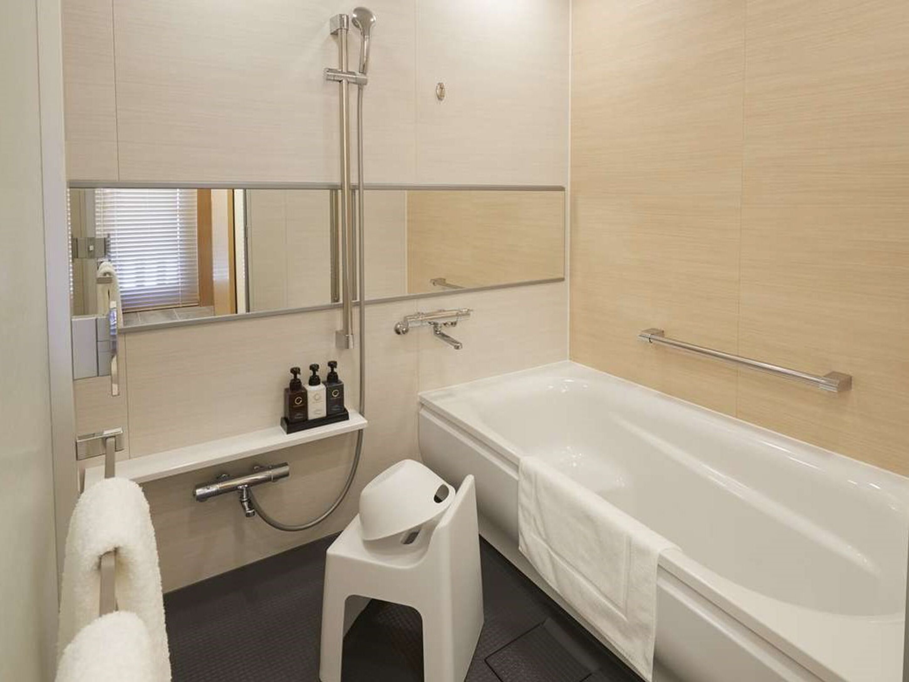 A modern bathroom with a bathtub, a shower, a toilet, and a small stool.