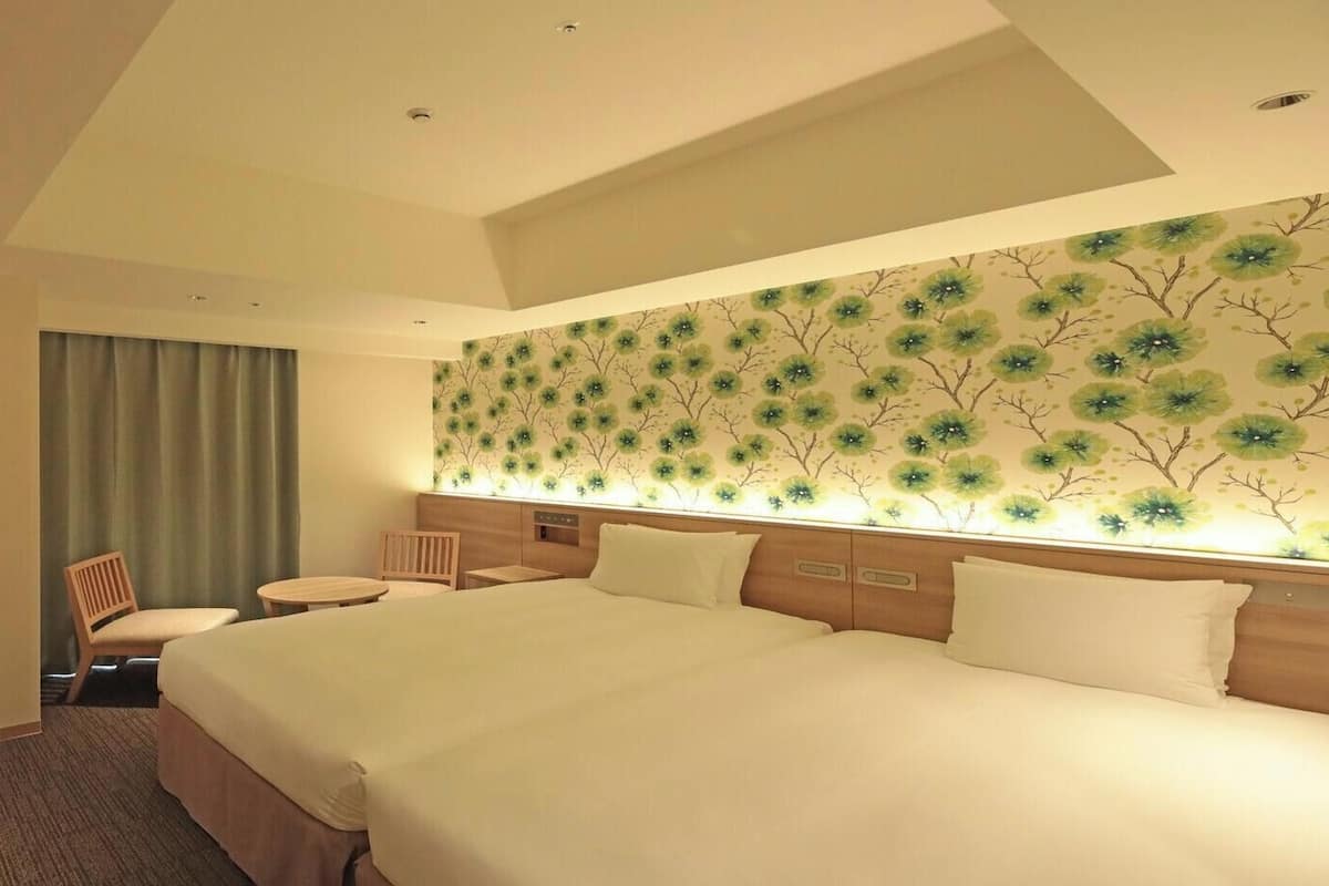 A hotel room with a large bed, a desk, a chair, and a television.