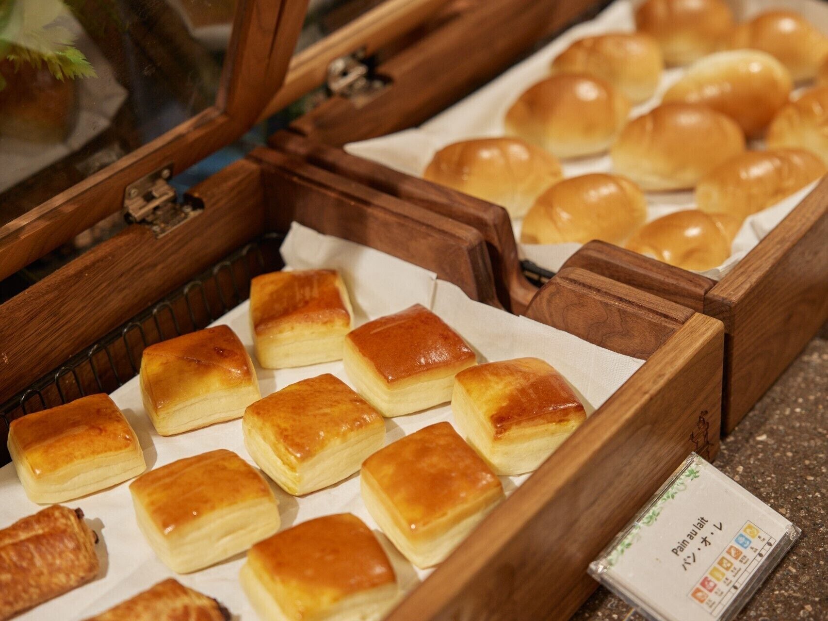 Een presentatie van diverse gebakken lekkernijen, waaronder rechthoekige en ronde gebakjes, gerangschikt in houten bakken.