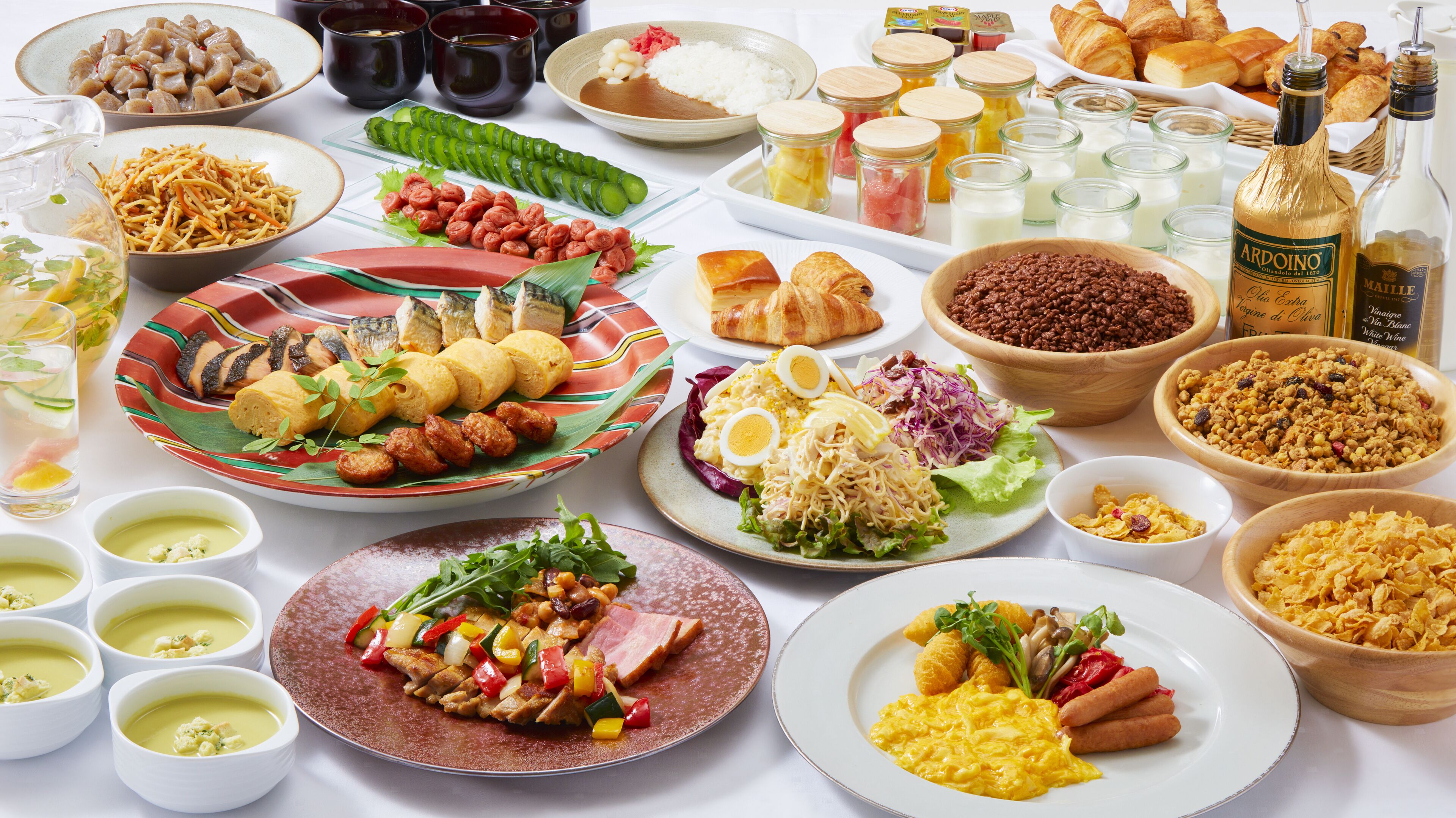 Una mesa con diferentes platos, entre ellos sushi, pan y ensaladas.