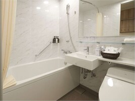 A bathroom with a bathtub, a sink, and a toilet. There is a shower curtain, a glass shelf with toiletries, and a mirror above the sink.