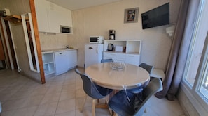 A compact kitchen with a microwave, coffee maker, and toaster. There is a round table with chairs and a window with curtains. - GRANDALLA  31 -1 apt 3 pers-Pas de la Casa- pie piste-006160 (PAS DE LA CASA)