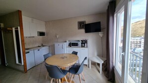 A compact kitchen with a dining table and chairs, a microwave, a coffee maker, and a TV mounted on the wall. - GRANDALLA  31 -1 apt 3 pers-Pas de la Casa- pie piste-006160 (PAS DE LA CASA)