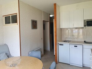 Eine kleine Küche mit weißen Schränken, einem Geschirrspüler und einem kleinen Fenster.