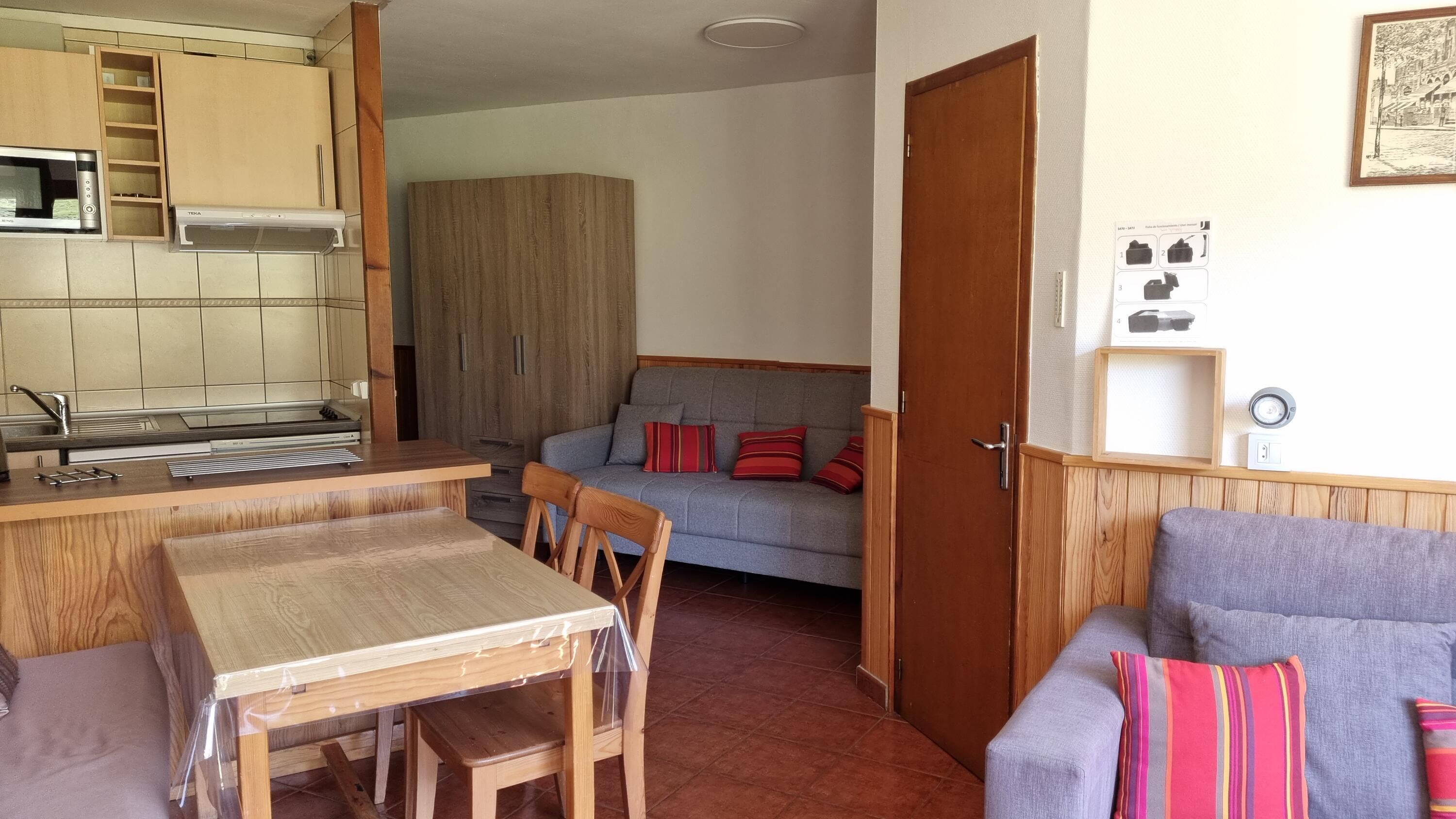 A compact living space with a kitchenette, a dining area, and a seating area with a sofa and chairs.