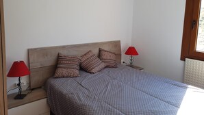 Una camera da letto con una testiera in legno, due comodini con lampade rosse e biancheria a motivi.
