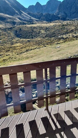 Une terrasse en bois offrant une vue sur un paysage montagneux.