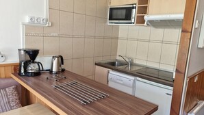 Una cucina compatta con macchina da caffè, bollitore e forno a microonde a parete.