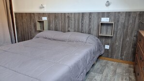 A bedroom with a bed, wooden headboard, bedside tables, and a dresser.