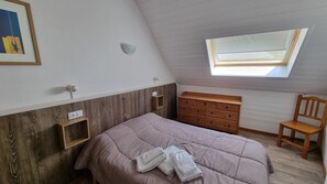 A bedroom with a sloped ceiling, a bed, a wooden dresser, a chair, a small shelf, and a skylight. - TETRAS 504-apt duplex-2 hab- 6pers-Pas de la Casa-005810 (PAS DE LA CASA)