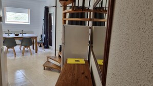 A room with a wooden table, chairs, a window, and a door with a curtain.