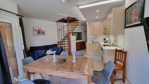 A compact living space with a dining area, kitchen, and a spiral staircase.