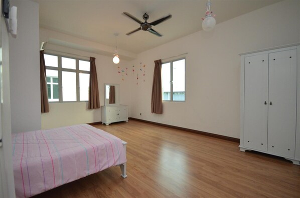 Un dormitorio amplio con cama, cómoda, armario y ventilador de techo.