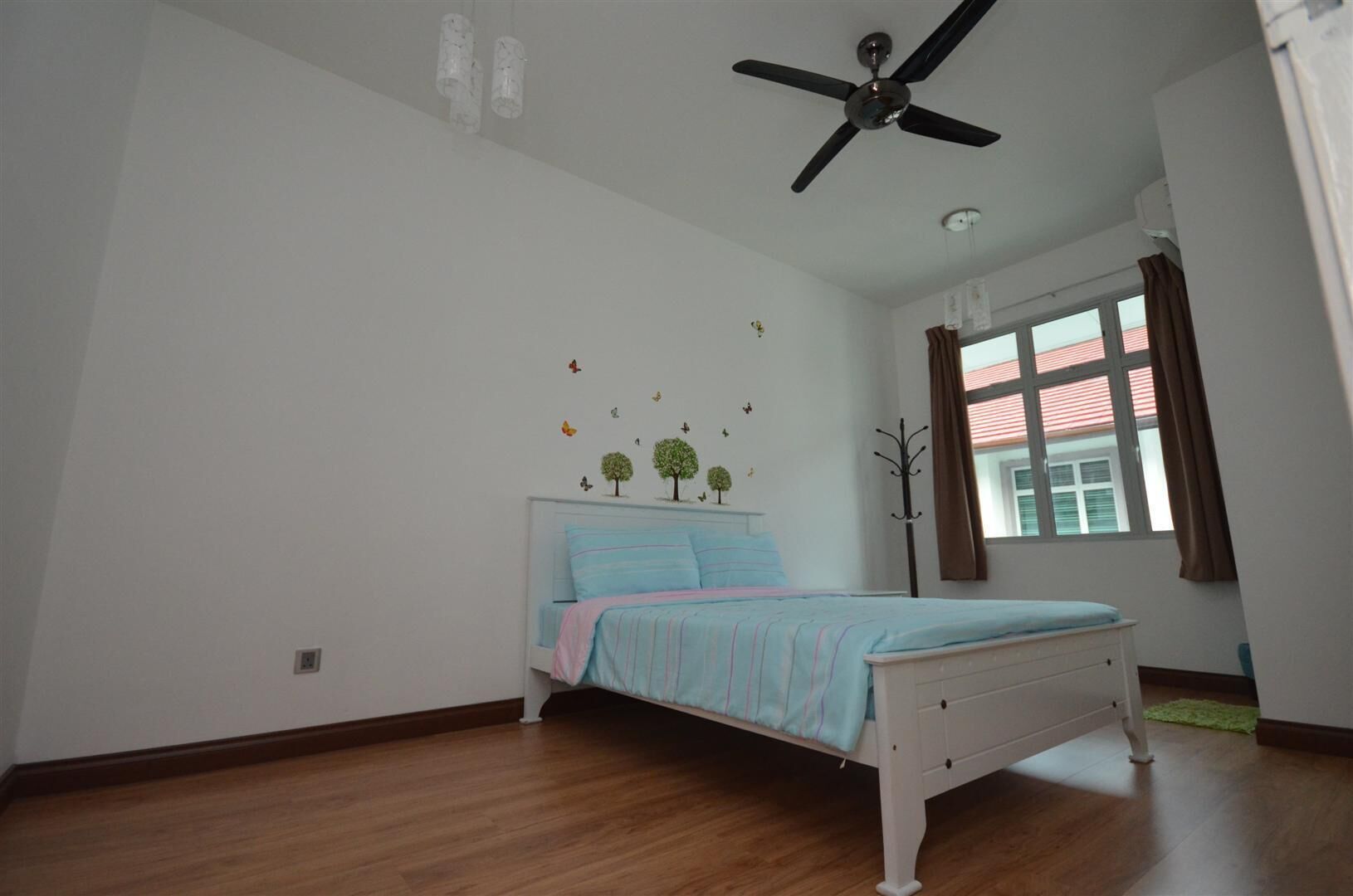 A bedroom with a bed, a ceiling fan, a window with curtains, and wall decals.