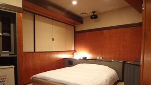 Una habitación de hotel con una cama, un escritorio con lámpara y un mini bar.