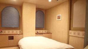 Una habitación de hotel con una cama grande, un tocador con espejo y una mesita con un jarrón de flores.