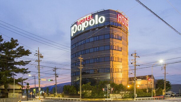 Hotel 'Hotel Popolo', con fachada de vidrio moderna y señalización iluminada.