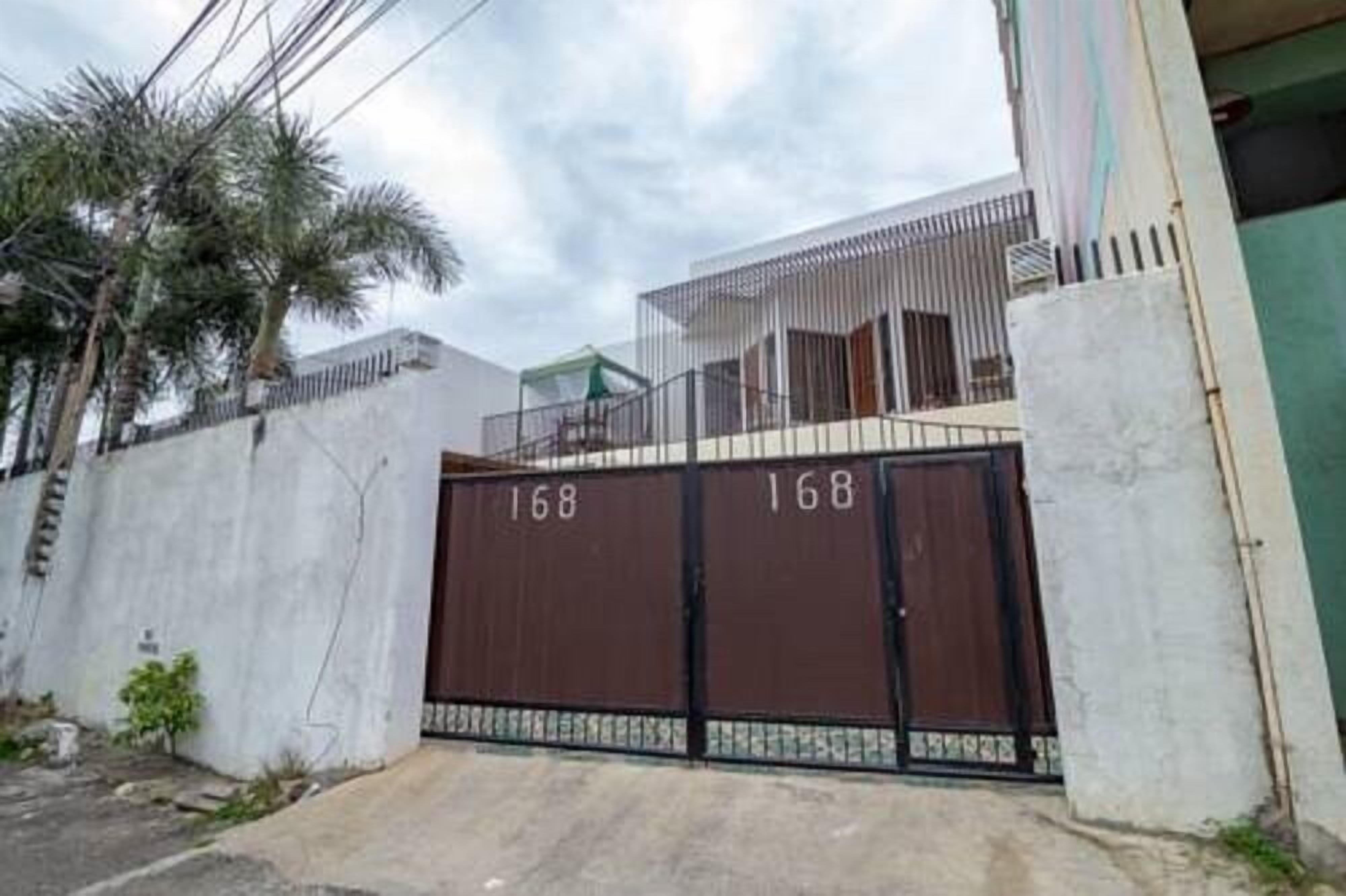 A gated residential area with a concrete wall and a metal gate marked with the number 168.
